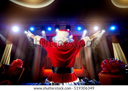 Dj Santa Claus for Christmas in the rays of light, with music at the event is back, put his hands up.
