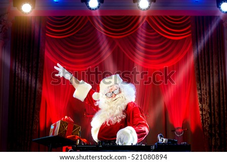 Dj  Santa Claus mixing at the party at Christmas, raised his hand up, the other hand holding a microphone.