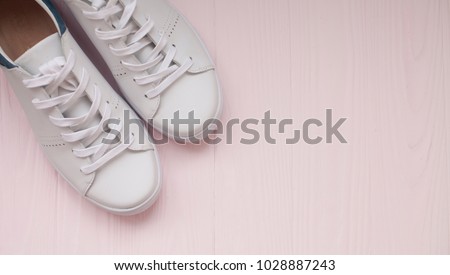 White sneakers on light pink background.Toned image. Women\'s shoes. \
stylish white sneakers