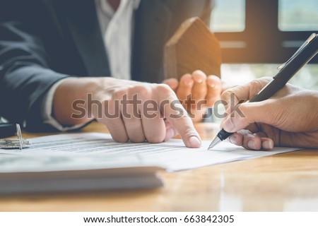 Close up of Business man pointing and signing agreement for buying house. Bank manager concept.