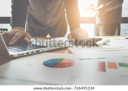 Close up Businessman using calculator and laptop for do math finance on wooden desk in office and business working background, tax, accounting, statistics and analytic research concept