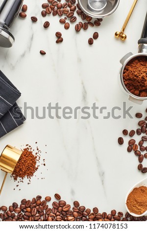 Flat lay of coffee background. Assorted coffee beans, ground and instant coffee, portafilter and tamper on marble background. Top view, copy space.