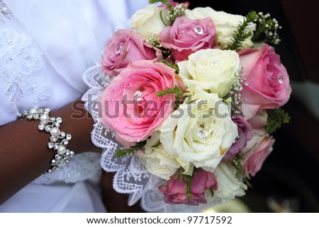 Bride holding bouquet with pink and white roses, African wedding.