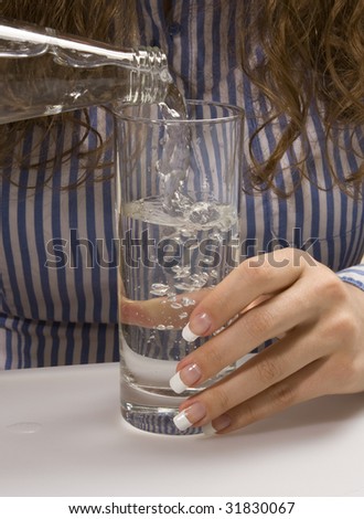 The girl pours water in a glass