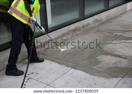 Pressure Washing. An unidentifiable city employee power washes blood or ketchup off a city sidewalk in downtown Los Angeles California.