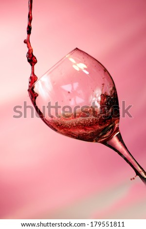 Red Wine pours into, onto, and around a wine glass filling it, spilling it and making a mess all over. Photographed with a fast shutter speed of up to 4000th of a second for beautiful stop motion.