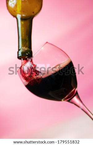 Red Wine pours into, onto, and around a wine glass filling it, spilling it and making a mess all over. Photographed with a fast shutter speed of up to 4000th of a second for beautiful stop motion.