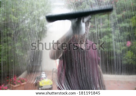 Window cleaner using a squeegee to wash a window.