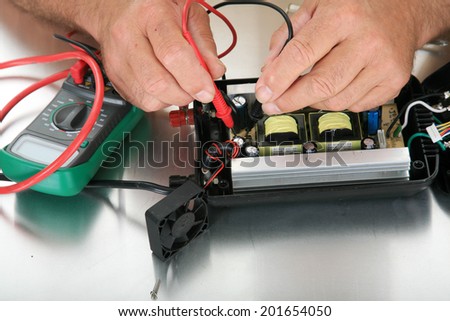 a person uses a voltage meter to check for dead circuits, faults and shorts in an electronic device.