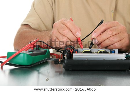 a person uses a voltage meter to check for dead circuits, faults and shorts in an electronic device.