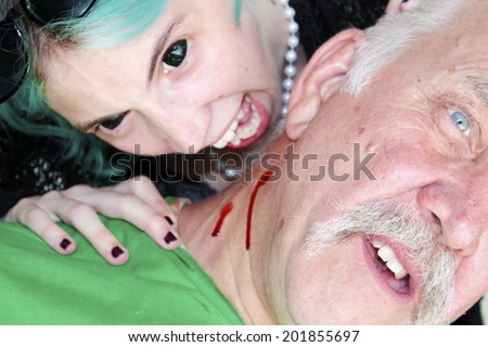 A Female Vampire with Blue Hair and Black Eyes Bites an unsuspecting victim and drinks his blood for her dinner. On white with room for your text