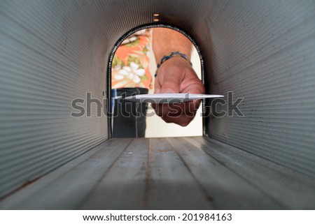 A Unique view of someone getting or placing mail in a mail box, shot from the Inside Out.