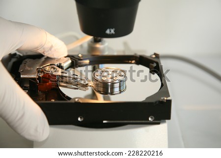 A skilled Computer Technician examines a Computer Hard Drive under a Microscope looking for flaws, scratches in the disc, and other issues to repair or replace. Computer Hard Drives are important