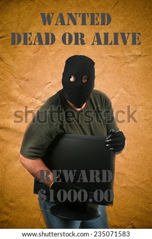 A genuine Bad Guy aka Burglar holds a stolen computer monitor while posing on a Wanted Dead or Alive poster.