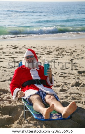 Santa Claus relaxing in his lounge chair on a tropical sandy beach - Christmas concept  Santa Claus loves to vacation when not having to work on Christmas Eve delivering gifts to good boys and girls.