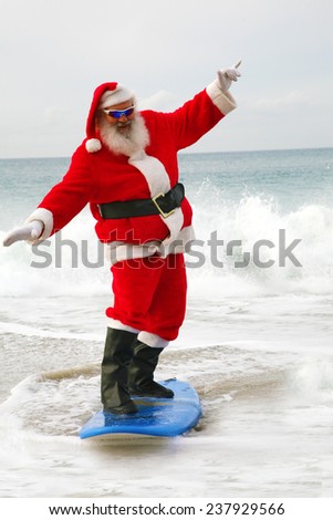 Surfing Santa Claus. Santa Claus rides on his surfboard as he rides the waves of the ocean blue. Santa Loves Sports the beach and the outdoors. Santa loves to surf on his surfboard as much as he can
