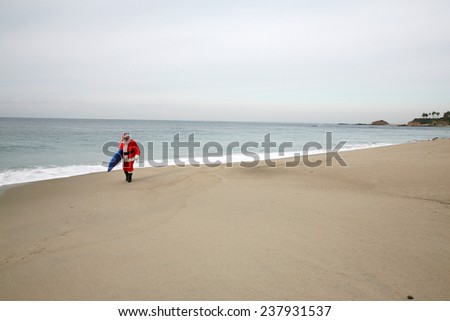 Surfing Santa Claus. A lonely Santa Claus walks on an empty beach with his Surfboard under his arm ready to go ride the waves alone. Reindeer and Elves do not surf so they leave Santa alone.