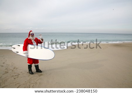 Surfing Santa Claus. Santa Claus holds his Blue Surfboard under his arm as he checks out the Waves at one of his Favorite Secret Surfing Spots. Santa loves Sports and Surfing. They call him Mr. Claus