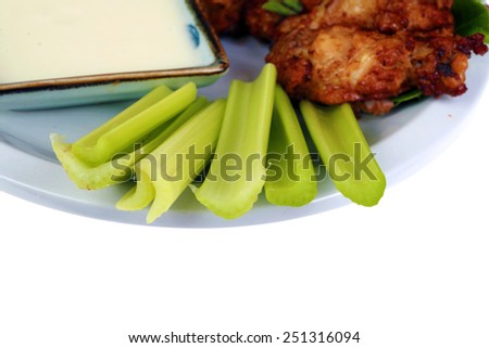 Buffalo Chicken Wings with Celery and Blue Cheese Dressing and Lettuce on a White Plate isolated on white with room for your text. Buffalo Wings are enjoyed by millions of people around the world.