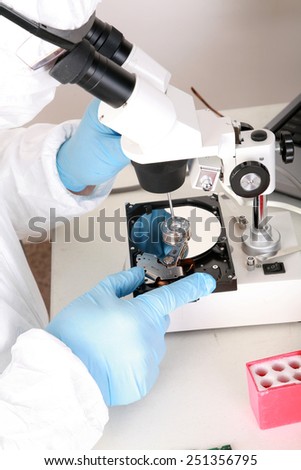 A Professional Computer Forensics Technician examines a Hard Drive under his microscope for microscopic damage and for information recovery of important and secret documents for clients.