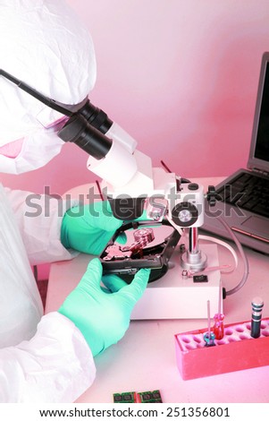 A Professional Computer Forensics Technician examines a Hard Drive under his microscope for microscopic damage and for information recovery of important and secret documents for clients.