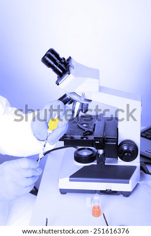 Laboratory examination of Ebola or Bio Hazard and Infectious Waste and Deseases. Scientist uses a microscope and computer monitor to study biological samples of deadly deseases