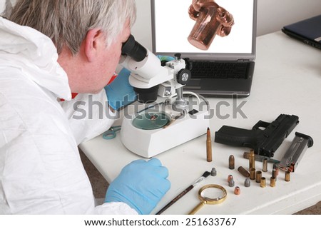 forensic analysis - a forensics lab technician examines a bullet and hand gun for finger prints, blood splatter, and any other residue or evidence to be used in a court case