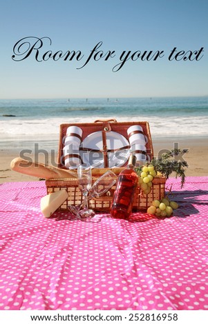 A beautiful Picnic in Laguna Beach in Southern California. Picnic Basket with French Bread, Wine, Grapes, Cheese, Flowering Rosemary Cuttings, and the Blue Paficic Ocean with Waves and Sand.