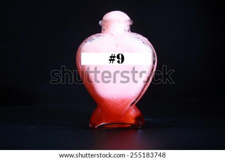 A Genuine Secret Recipe Love Potion in a Heart Shape Bottle isolated on black with room for your text