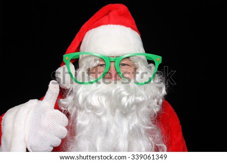 Santa Claus wears Giant Green Glasses while he poses for photos in a Photo Booth. Santa Claus humor. Santa Claus Joking around. Christmas Humor. Funny photo. Funny image. Laughing Santa.