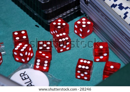 dice sit on a green felt card table with chips and other things you would use in gambling