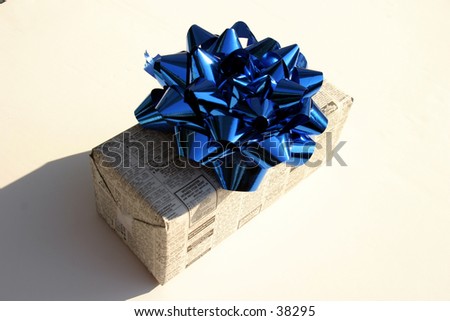 a x mas present wrapped in newspaper with a blue bow on a white and nice shadows