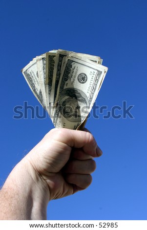 american cash being held tight in the fist of a real humanbeing against a blue sky background