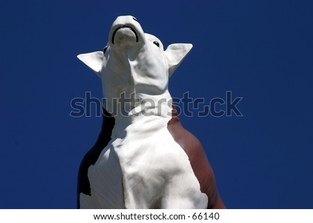 a plastic cow in the sky part of a butcher market sign