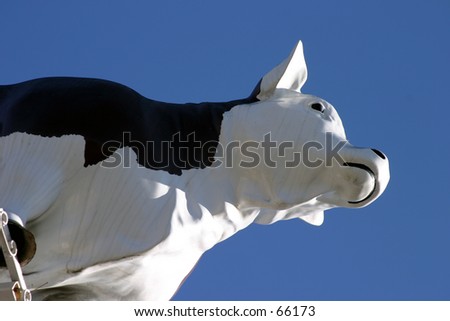 a plastic cow in the sky part of a butcher market sign