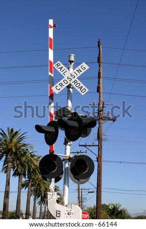 rail road crossing sign and lights and guards against a blue sky