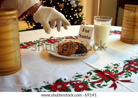 Santa Claus reaches for a cookie kindly left for him from a nice lady on x mas eve