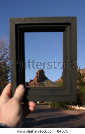 Bell Rock in Sedona Arizona is framed by a black picture frame held by the photographers hand
