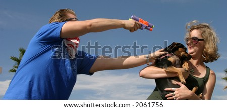 a crazy bad guy holds up a young woman  for her dog with a squirt gun