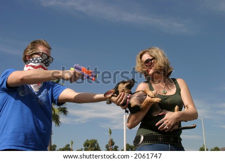 a crazy bad guy holds up a young woman  for her dog with a squirt gun