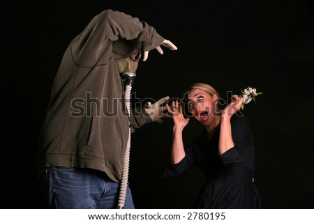 an innocent young woman shreaks in fear as she is about to be attacked by a gas mask wearing fiend in an apocylopic post nuclear future