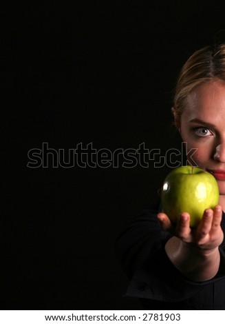 a healthy fit woman hands a fresh green apple to YOU the viewer healthy eating concepts eve passing adam an apple from the tree of knowledge concept