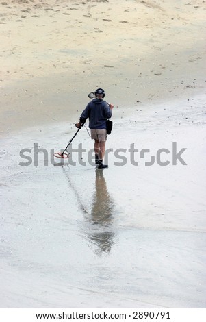 a unidentifiable person searches for burried Treasure with a metal detector in Huntington Beach California aka Surf City