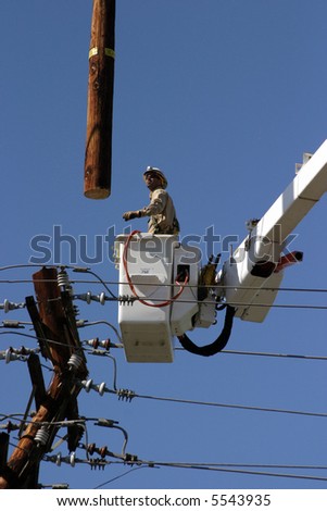 Workers in a man lift aka bucket lift prepare to remove and replace a 95 foot utility pole broken by a car accident