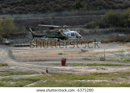 orange county sheriff heliocopters with water buckets attached prepair for flight at a reservoir at the Santiago Canyon wild fires