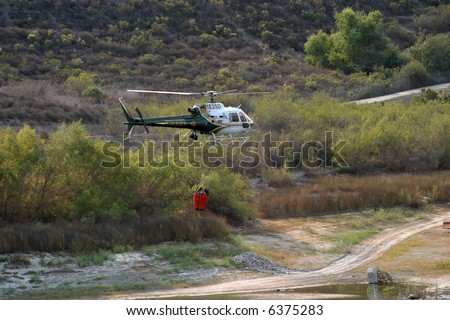 orange county sheriff heliocopters with water buckets attached prepair for flight at a reservoir at the Santiago Canyon wild fires