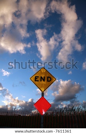an End sign sits at the end of a road against a Blue Sky with Amazing fluffy clouds