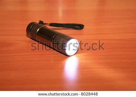 a Mulit Bulb LED flashlight lays on a table emitting bright light while turned on