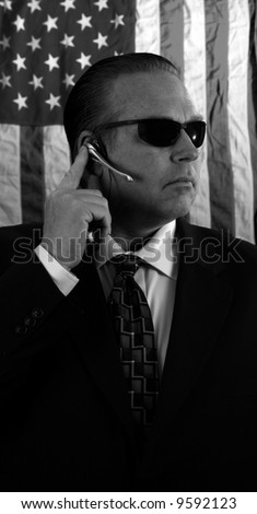 a Secret Service Agent speaks on his ear piece in black and white