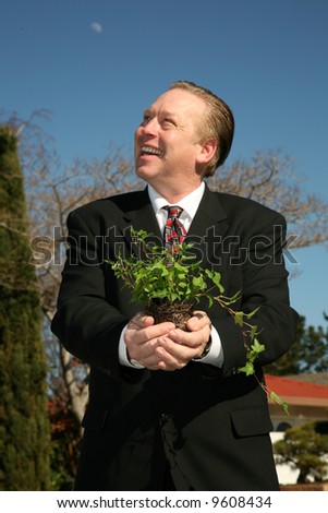 an environmentally friendly business man in a nice suit holds a green plant to save the earth from Global Warming